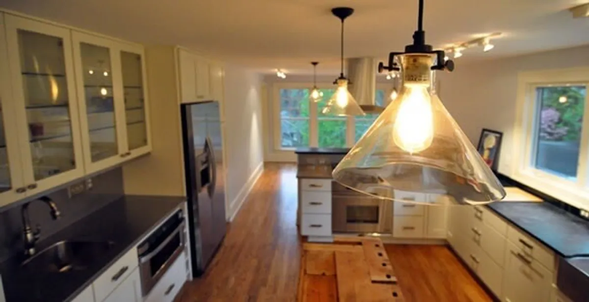 Residential electrician installing modern indoor light fixture in a home in Denver, CO